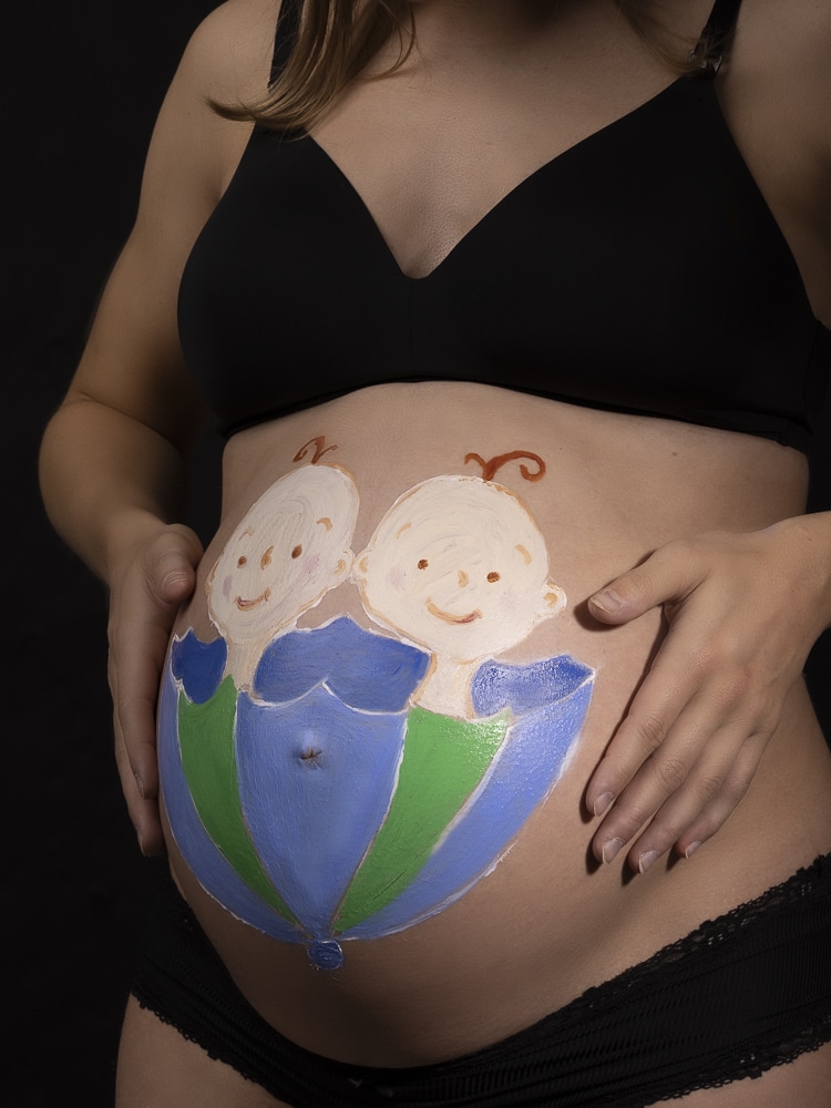 Kvinna gravid med tvillingar och tv&aring; sm&aring; bebisar m&aring;lande p&aring; sin mage | Foto av Fotograf Link&ouml;ping