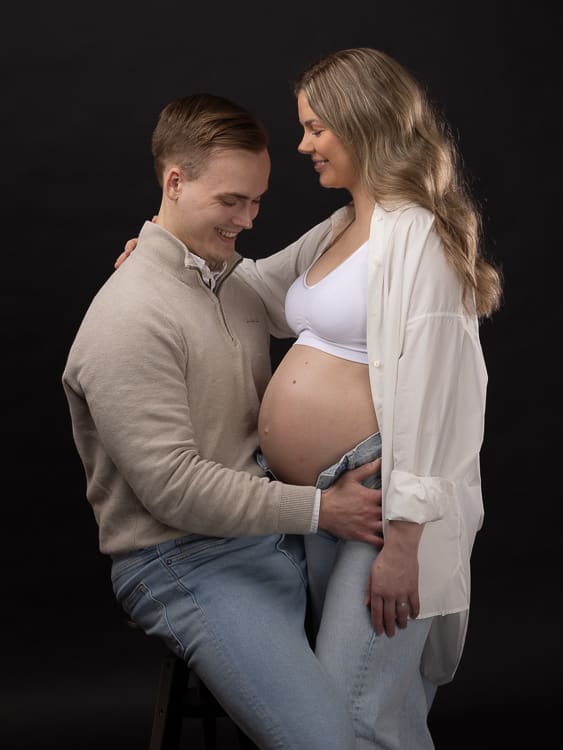 Ett ungt par poserar i studion hos Fotograf Link&ouml;ping f&ouml;r en gravidfotografering.